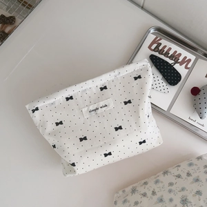 Detail of light grey cotton makeup bag with black bow pattern and drawstring closure