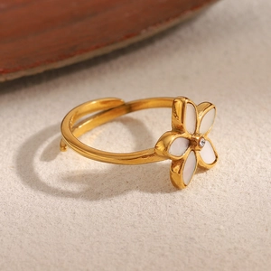 Gros plan d'une bague fleur dorée avec pétales blancs et zircon étincelant