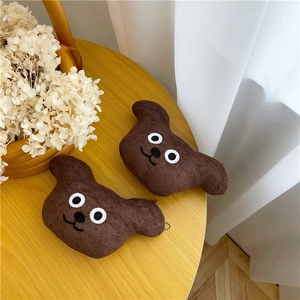 Close-up of two cute brown plush bear keychains with metal chains on a warm yellow table