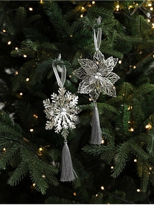 Detail of silver snowflake ornaments with tassels hanging on a festive Christmas tree