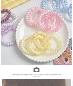 Makroaufnahme von pastellfarbenen Spiral-Haargummis in einer dekorativen Porzellanschale