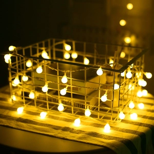 Close-up of warm yellow LED ball string lights wrapped on a decorative iron basket