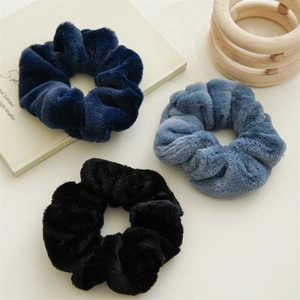 Detailed view of three soft rabbit fur scrunchies in navy, grey blue, and black colors