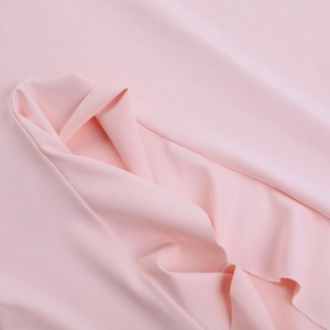 Gros plan du tissu rose montrant une texture soyeuse et un drapé pour robe fendue