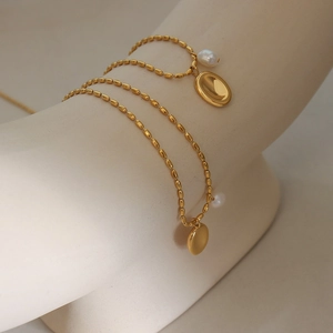 Gold plated stainless steel necklace with oval pendant and freshwater pearl on mannequin