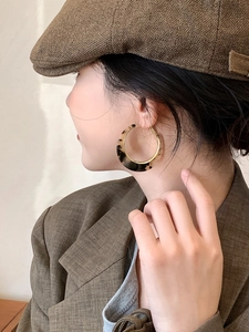 Detail of leopard print velvet hoop earrings with golden metal edges on a model