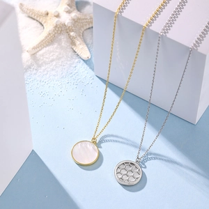 Detail of silver shell and honeycomb pendants on white geometric blocks with sea stars