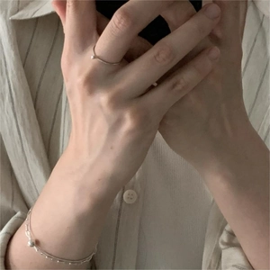Detail shot of minimalist V-shaped silver ring and thin bead chain bracelet on hand