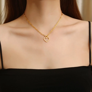Elegant gold heart pendant necklace with shimmering crystals on a paperclip chain worn by model
