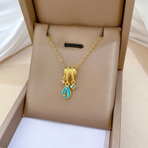 Detail of luxury gold titanium necklace with blue teardrop and star charms on velvet
