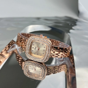 Close-up of a vintage square rose gold watch with rhinestone bezel on a reflective surface