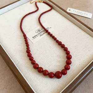 Détail du collier de perles rouges avec fermoir mousqueton doré et chaîne réglable