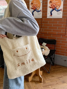 Winterlicher Plüsch-Shopper aus Lammwolle mit Smile-Stickerei am Modell präsentiert