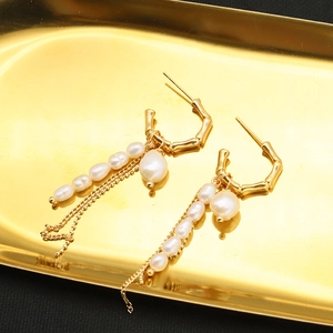 Elegant gold plated bamboo hoop earrings with natural pearl tassel on a golden tray