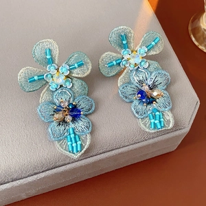 Macro shot of blue embroidered flower earrings with rhinestones, beads and sequins