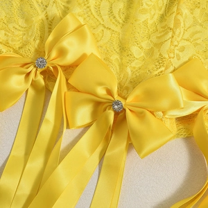 Détail de dentelle jaune avec un nœud en satin et boucle décorative en strass brillant