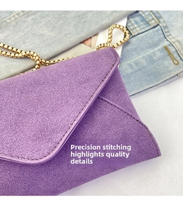 Detail shot of precision stitching on a purple suede envelope bag with gold chain