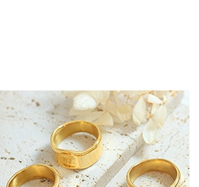 Detailed view of three gold ripple rings with organic wavy textures on a stone base