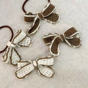 Detailed view of four knitted bow hair ties in brown and cream with contrast stitching