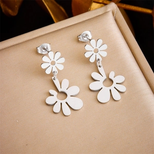 Elegant silver hollow daisy earrings in stainless steel on a champagne silk jewelry box