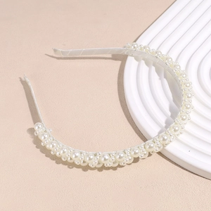 Macro detail of the elegant faux pearl headband with dense luster beads and ivory satin wrap