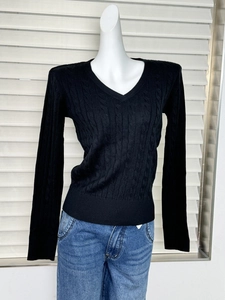 Detail of classic cable knit texture on a black V-neck slim fit sweater for women