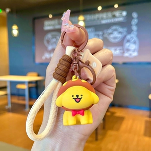 Detailed view of cartoon yellow puppy keychain with beige woven strap and brown clasp