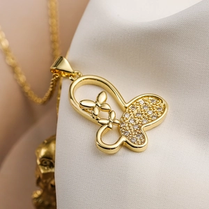 Close-up of a gold butterfly pendant necklace with clear zircons on white silk fabric