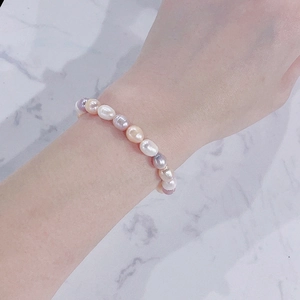 Detail of freshwater pearl and jade bracelet worn on wrist over marble background