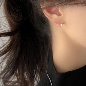 Close-up of minimalist gold cubic zirconia stud earring worn on earlobe for daily style