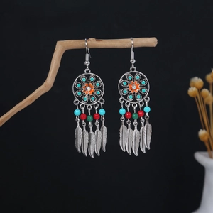 Detail of bohemian silver earrings with colorful beads and metallic feather pendants