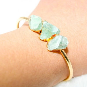 Detail of adjustable gold-plated cuff featuring three natural raw green crystal stones