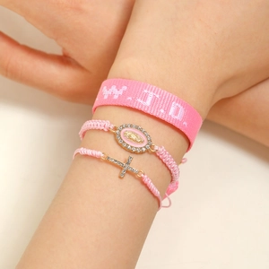 Detail of pink WWJD woven wristband with rhinestone cross and Virgin Mary charms