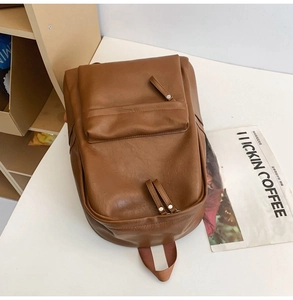 Detailed macro view of the brown PU leather texture and zip pocket on this retro backpack