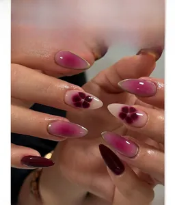 Detail of purple almond press-on nails with floral art and golden accents