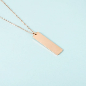Detailed view of vertical rose gold rectangular bar pendant on slim link chain