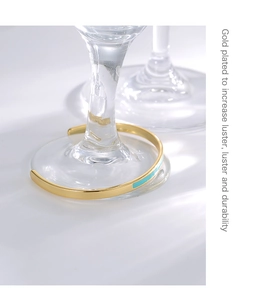 Detail of gold-plated bangle with tiffany blue enamel on a glass base background