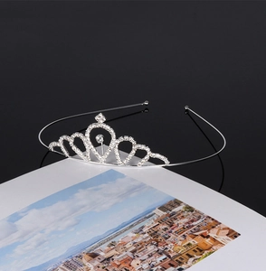 Detail of silver bridal crown with crystals placed on a book against a dark background