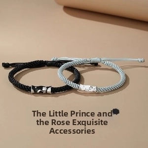 Close-up of Little Prince and Rose engraved metal charms on woven couple bracelets