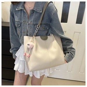 Dettaglio della borsa tote bianco avorio con catena argento e portachiavi rosa