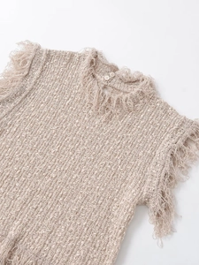 Detailed view of beige knit vest showing textured fabric and fringe edge craftsmanship