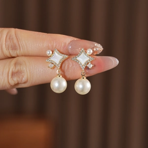 Vue détaillée des boucles d'oreilles étoile dorée avec perles, cristaux et incrustation nacre