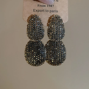 Detailed close-up of vintage oval drop earrings with grey rhinestones and metal finish