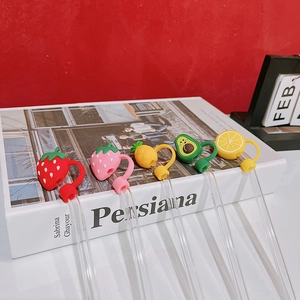Borosilicate glass straws with cute silicone fruit toppers on a decorative book