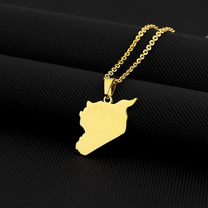 Detailed close-up of golden Syria map pendant on a textured black fabric background