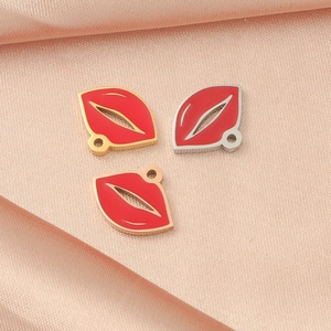 Detailed macro view of gold, silver and rose gold lip-shaped enamel pendants on pink silk