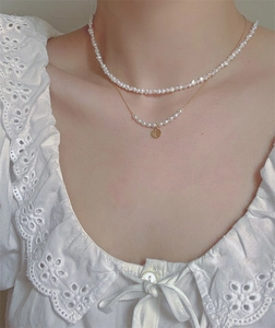 Detail of layered baroque freshwater pearl necklace with gold Fu character pendant