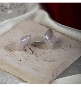 Macro shot of S925 silver earring posts with baroque square pearls on stone base
