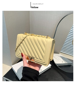 Detailed view of yellow quilted faux leather crossbody bag with gold chain and turn lock