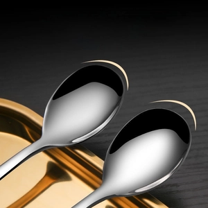 Close-up of polished stainless steel spoon with rounded edges on a dark wood background